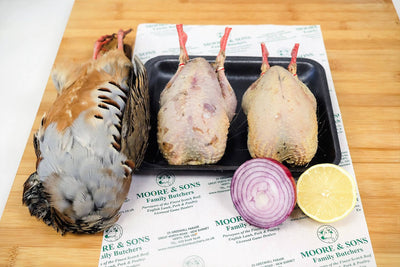 three partridges on a butchers block with onion and lemon on the side