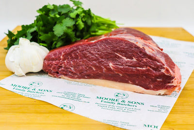 picanha on a butcher block with herbs and garlic on the side