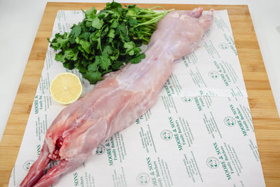 rabbit meat on a butchers block with herbs and lemon on the side